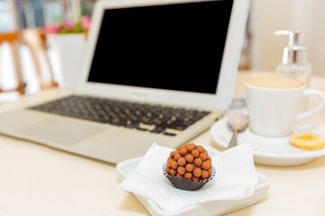 Blank screen laptop computer and a cup of coffee in modern meeting room in a bar.