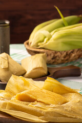 Brazilian corn snack pamonha and cornflower arranged on a table with green and white tablecloth, selective focus.