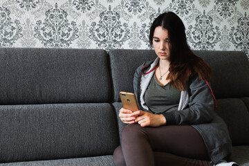A woman is typing a text message on a smartphone, work from home, distant work. Photo of a young woman, communicating with followers using a mobile phone. Quarantined free time, copy space, banner