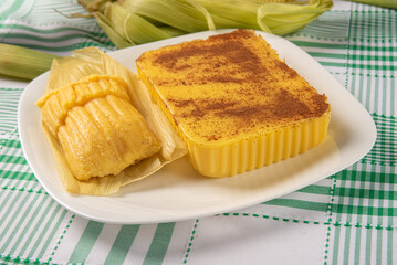 Brazilian Cural, candy corn and pamonha, corn on the cob arranged on a table with a green and white tablecloth, dark background, selective focus.