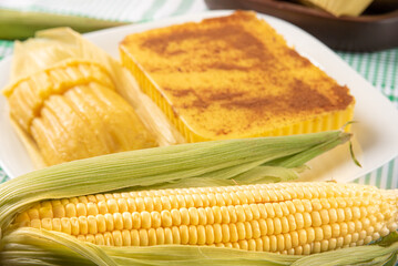 Brazilian Cural, candy corn and pamonha, corn on the cob arranged on a table with a green and white tablecloth, dark background, selective focus.
