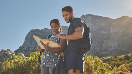All I need is summer sunshine and a guide. Shot of a young couple using a guide book to complete a hike in a mountain range.