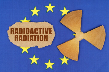 On the flag of the EU, the symbol of radioactivity and torn cardboard with the inscription - Radioactive Radiation