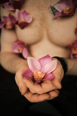 Handsome man holds orchid flower in hands. Fragile flower in strong male hands
