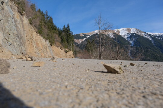 Small Broken Stones And Rocks On The Ground, Low Angle Photo Of Rock And Snow Mountain Peak And Summit Background.