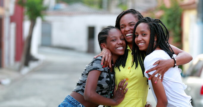 Loving mother and teen daughters embrace. MIxed race teenage girls hugging mom