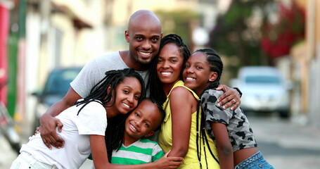 Happy African family portrait standing for photo outside. Cheerful black parents and children