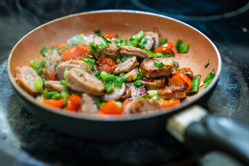Sausage and vegetables frying in a pan.