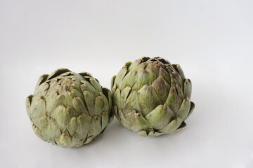Obraz premium Two Raw Artichokes Against White Background