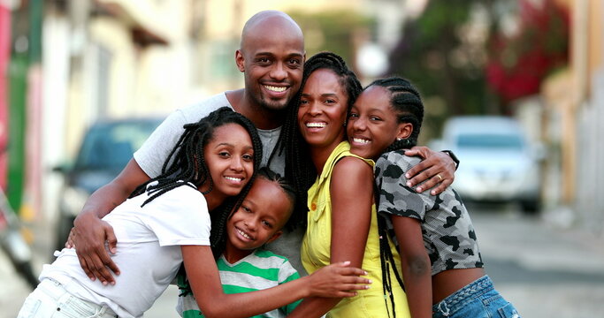 Happy African family portrait standing for photo outside. Cheerful black parents and children