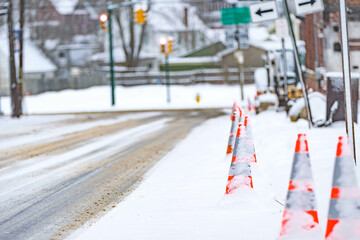 Road cones on the street around road work during snow storm.