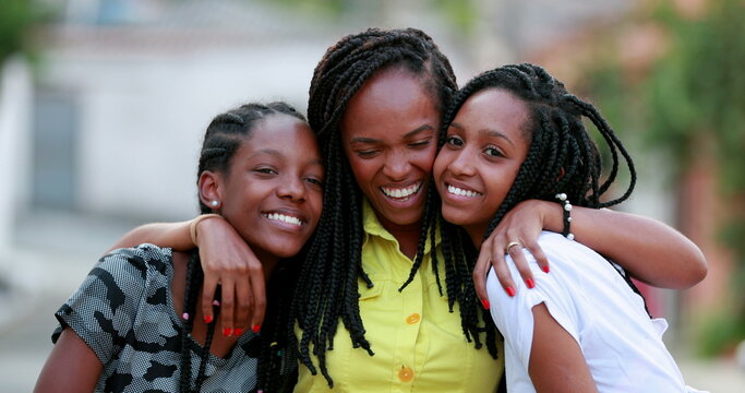 Funny mother hugging daughters outside. African black ethnicity family love and affection