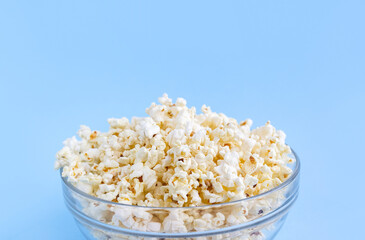 Popcorn bowl on blue background close up. Home television concept. Selective focus, copy space