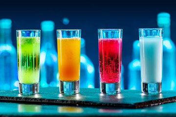 Cocktails Party Shots and Shooters on bar counter in a restaurant, pub. Miniature mixed drinks. Alcoholic cooler beverage at nightclub on dark background