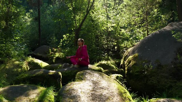 A girl practices yoga in the forest