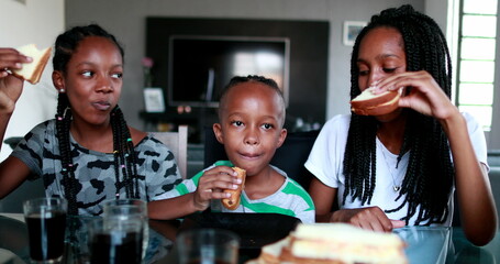 Children eating afternoon snack at home. Black African ethnicity kids snacking sandwiches