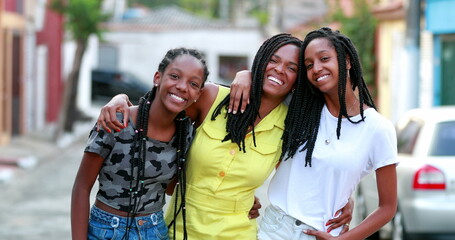 Casual happy mother and teen daughters standing outside. Authentic interaction. African ethnicity