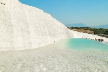 Natural travertine pools and terraces in Pamukkale. Cotton castle in southwestern Turkey. Tourists walking and bathing in Natural travertine pools