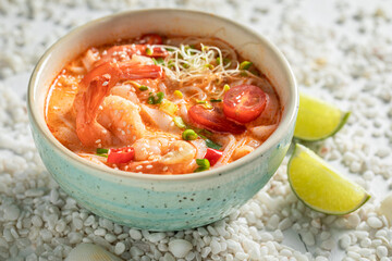 Spicy Tom Yum soup in blue bowl with lime.