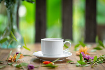 A white cup is set on a wooden table decorated with flowers.