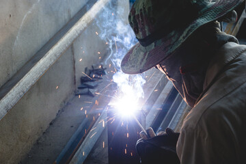 A welder is welding steel structures at a construction site.
