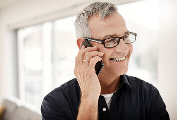 Its so nice to hear from you again. Shot of a mature man talking on a cellphone at home.