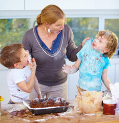 Caught in the act. Two boys being scolded by their mother for messing up her kitchen.