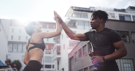 I believe in you. Shot of a young couple giving each other a high-five while standing outside in sportswear.