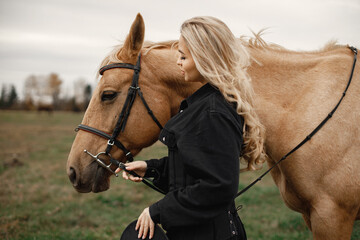 Obraz premium Beautiful blonde woman with blonde hair and a brown horse in the field