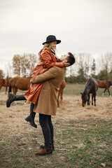 Romantic couple walking in the field with horses