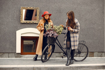 Two young girls standing near bicycle with a flowers and chatting