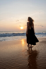 Fototapeta premium Beautiful woman at sunset on the beach