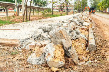 Fototapeta premium Focus on broken concrete fragments and blur the punching car running in front. Drilling and demolishing the concrete pavement of the roadside pavement.