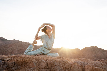 Woman practicing yoga in the mountains in the desert - 492299107