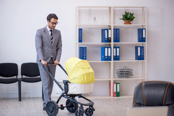 Young male employee looking after new born at workplace
