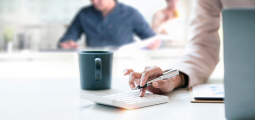 Business woman or accountant working Financial investment on calculator with calculate Analyze business and market growth on financial document data graph and laptop computer at office.