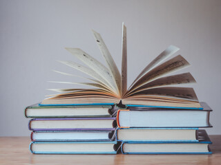 A simple composition of many books, stack or pile of books on wooden table, one of them open with copy space.