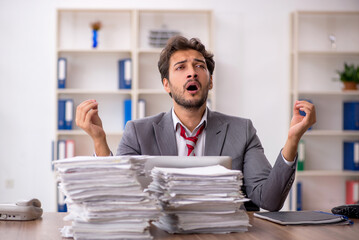 Fototapeta premium Young male employee unhappy with excessive work in the office