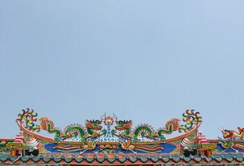 Colorful Chinese dragon statues on the roof of an ancient Buddhist temple, set in the lower portion...