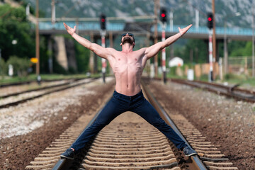 Model Flexing Muscles Outdoors at Railroad