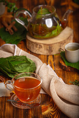 Obraz na płótnie Canvas Cup of Kratom tea with fresh green kratom leaf or Mitragyna speciosa on wood background.