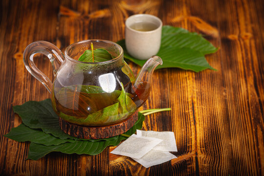 Cup of Kratom tea with fresh green kratom leaf or Mitragyna speciosa on wood background.
