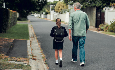 Education plays a crucial role in empowering our little princesses. Full length shot of a young school girl walking with her grandfather to school in the streets in their neighborhood.