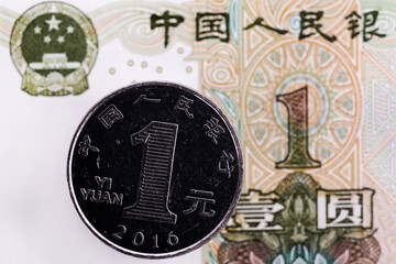 A coin in denomination of one Chinese yuan against the background of a fragment of a one-yuan note