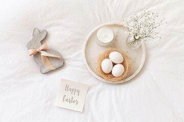 Marble tray, nest with white eggs, decorative bunny figure, candle, gypsophila flowers and card...