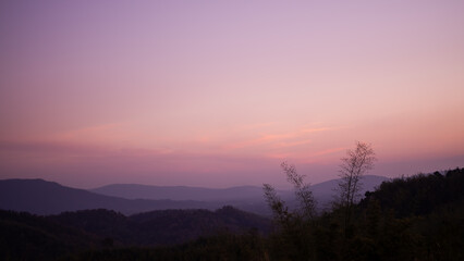 Sunset twilight gradient purple pink night sky with mountain forest and fog backgrond.  sweet wallpaper with free space. in sunrise evening of spring season. nature lanscape of thailand.