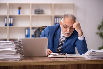 Fototapeta premium Old male employee working in the office