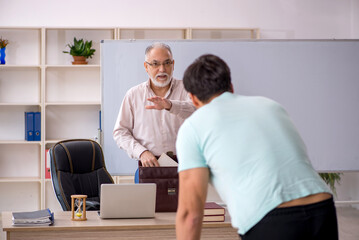 Old male teacher and young male student in the classroom