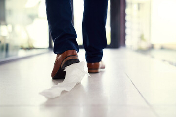 Dragging his embarrassment along. Closeup shot of a businessman walking in an office with toilet paper stuck to his shoe. - obrazy, fototapety, plakaty