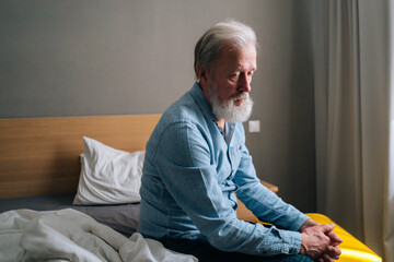 Frustrated gray-haired worried senior old adult male sitting alone at home thinking of lonely life....